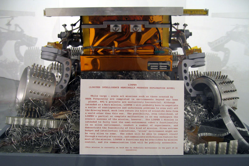 Limited Intelligence Marginally Produced Exploration Rover (LIMPER)
2007, aluminum, urethane, acrylic, mylar, cardboard, paper, Kapton, electronics, 12 3/4 x 31 x 21 inches (32 x 79 x 53 cm)
Front detail showing wheels, cameras and range finding systems.